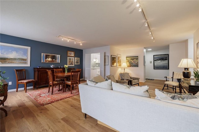 living area with baseboards, track lighting, and light wood-style floors