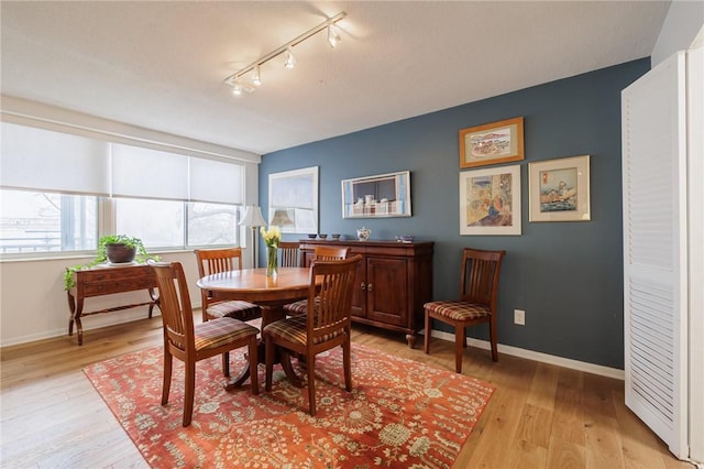 dining area with track lighting, light wood-style flooring, and baseboards