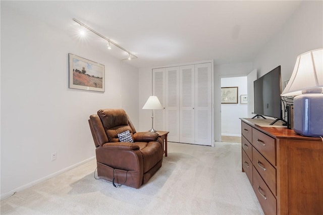 living area featuring light carpet, baseboards, and track lighting