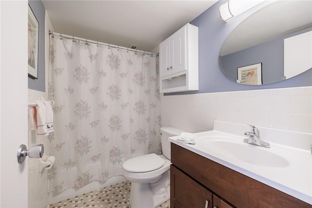 bathroom with tile walls, toilet, and vanity