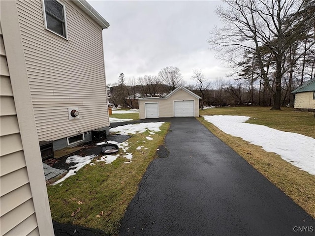 view of side of property with a detached garage, aphalt driveway, a lawn, and an outdoor structure