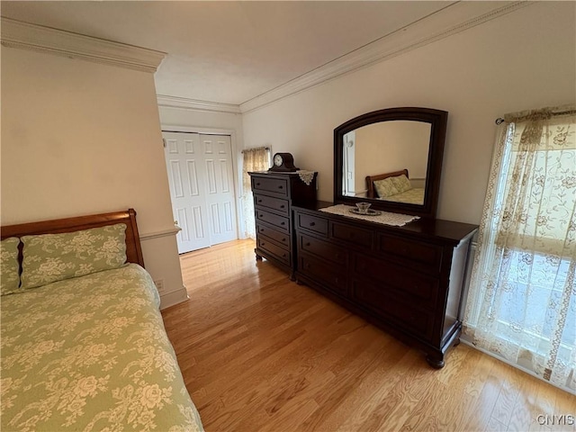 bedroom with light wood finished floors, ornamental molding, and a closet