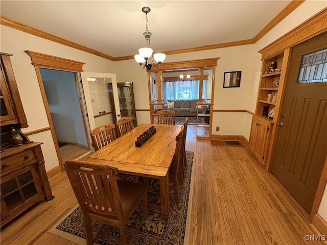 dining space featuring baseboards, ornamental molding, wood finished floors, and an inviting chandelier