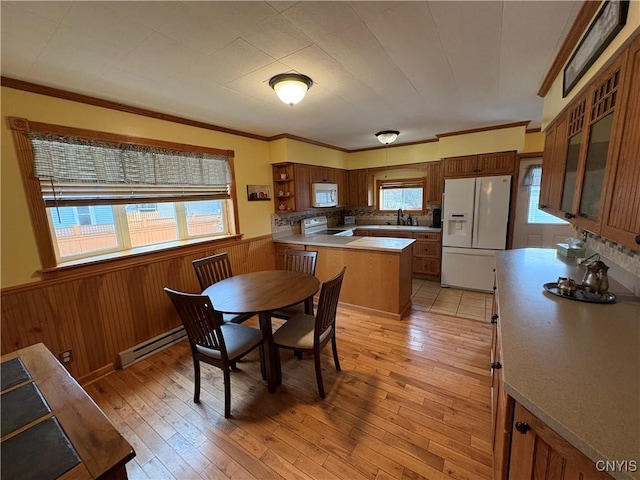 dining room with a wainscoted wall, baseboard heating, light wood-style flooring, and crown molding