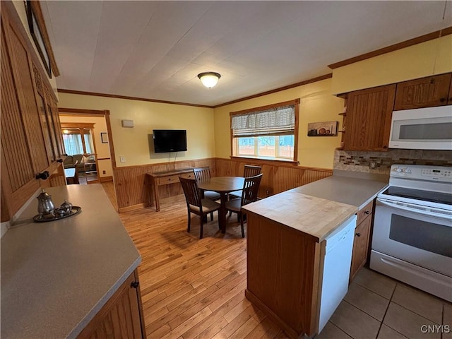 kitchen with ornamental molding, wainscoting, light wood-type flooring, white appliances, and a peninsula