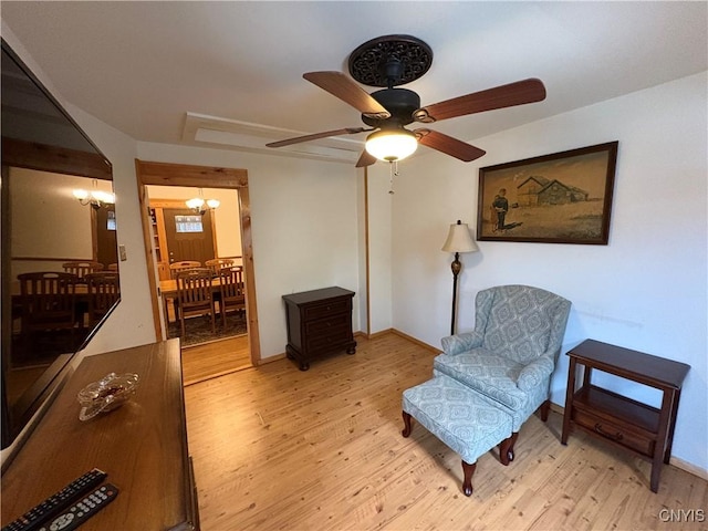 living area with light wood-style floors, baseboards, and a chandelier