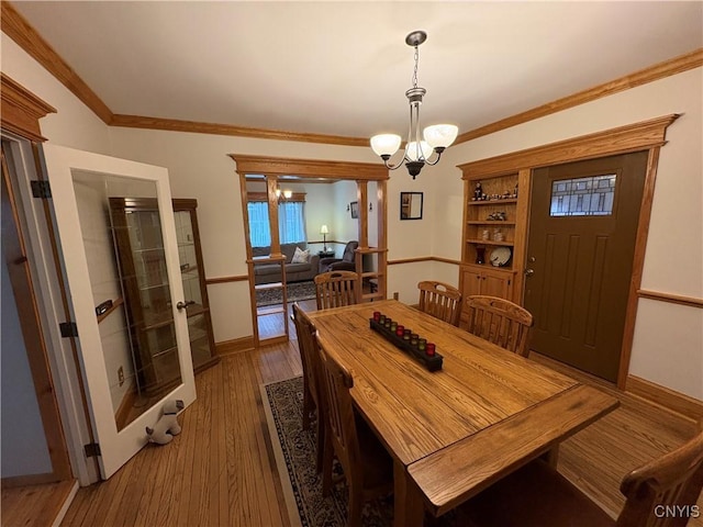 dining room featuring baseboards, crown molding, a chandelier, and wood finished floors