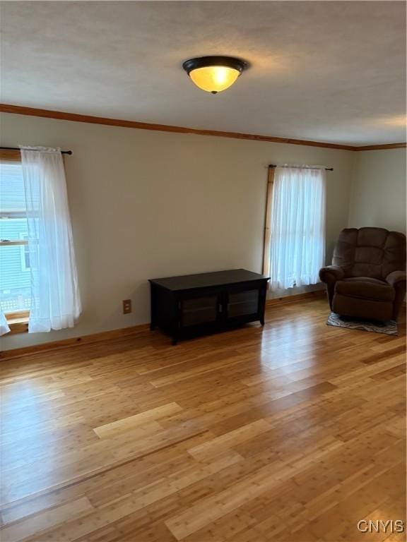 sitting room featuring light wood-style flooring, ornamental molding, and a wealth of natural light