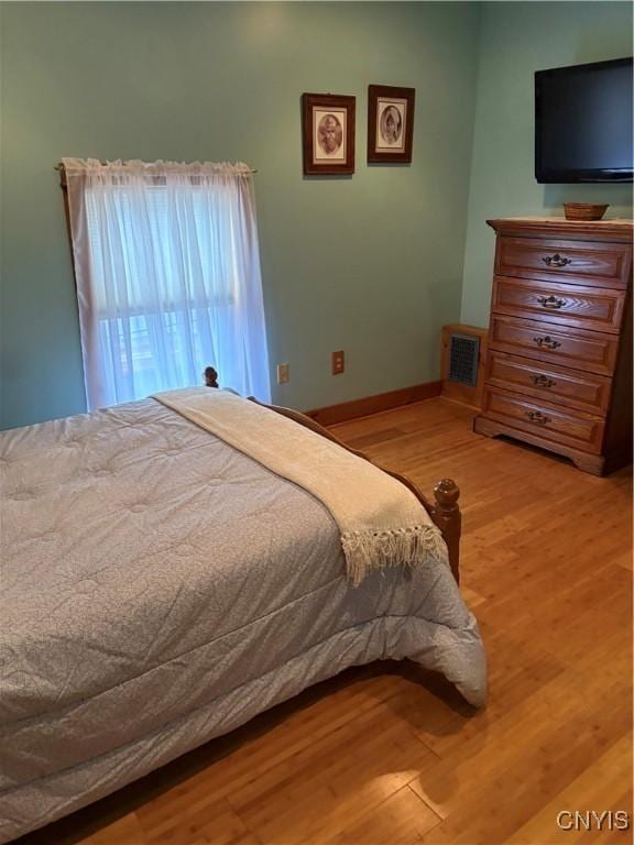 bedroom featuring wood finished floors, visible vents, and baseboards