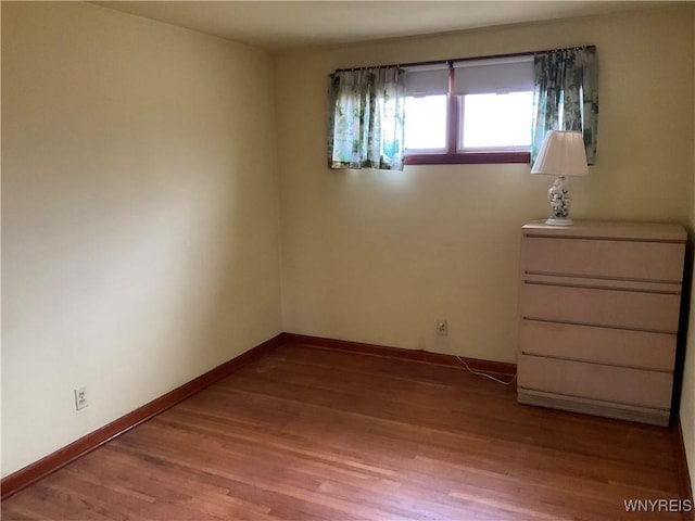 unfurnished room with light wood-type flooring and baseboards