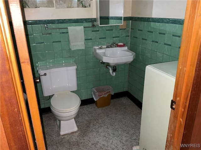 bathroom featuring a wainscoted wall, a sink, tile walls, and toilet