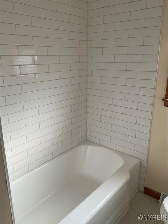 bathroom featuring a washtub, toilet, and baseboards