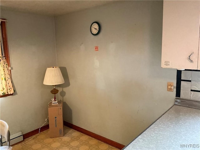 hallway with light floors, a baseboard radiator, and baseboards