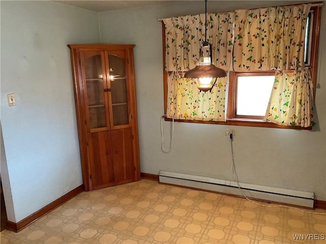 unfurnished room featuring a baseboard heating unit, baseboards, and light floors