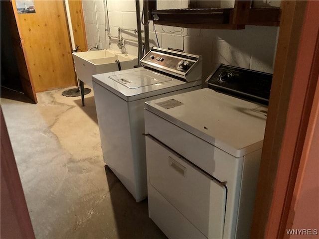 laundry area with independent washer and dryer, a sink, and concrete block wall