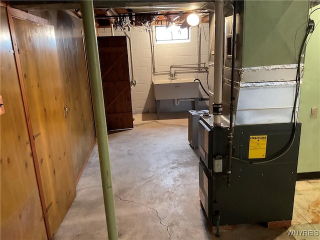 below grade area featuring a sink, concrete block wall, and heating unit