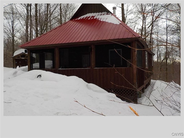 snow covered structure with a sunroom