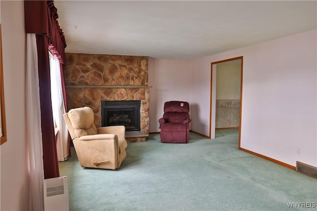 living area with radiator, carpet, baseboards, and a stone fireplace