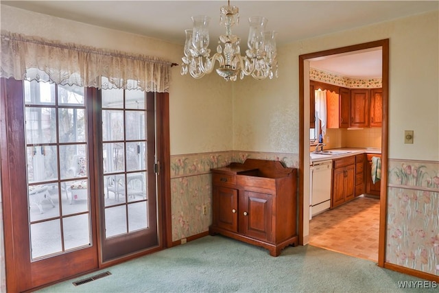 interior space with a chandelier, light colored carpet, a wainscoted wall, and a sink