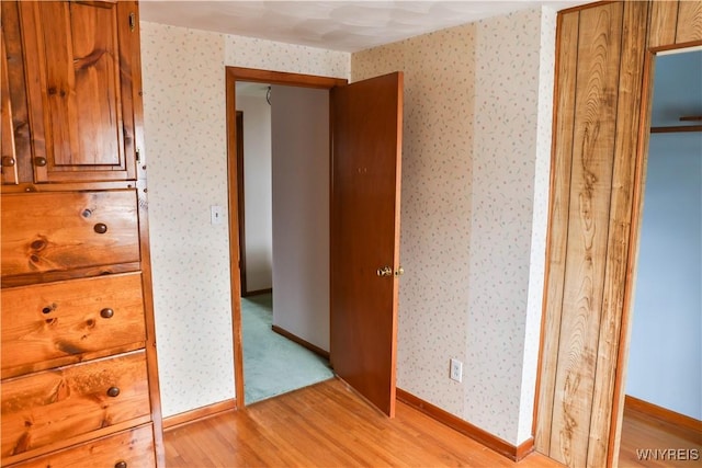 interior space with wallpapered walls, baseboards, and light wood-style floors