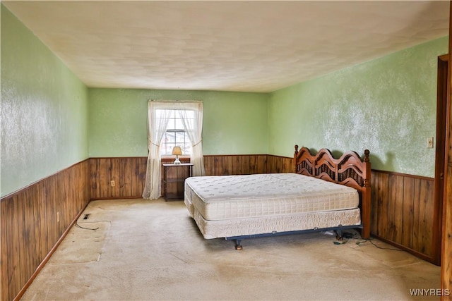 carpeted bedroom with a wainscoted wall and wooden walls