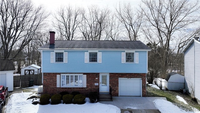 colonial-style house with a garage, brick siding, fence, and a chimney