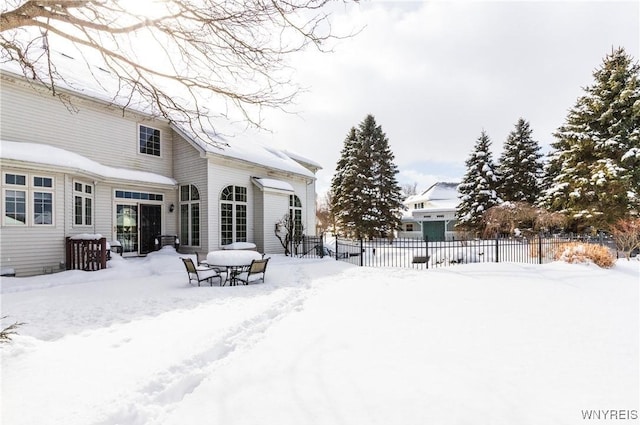 snow covered house featuring fence