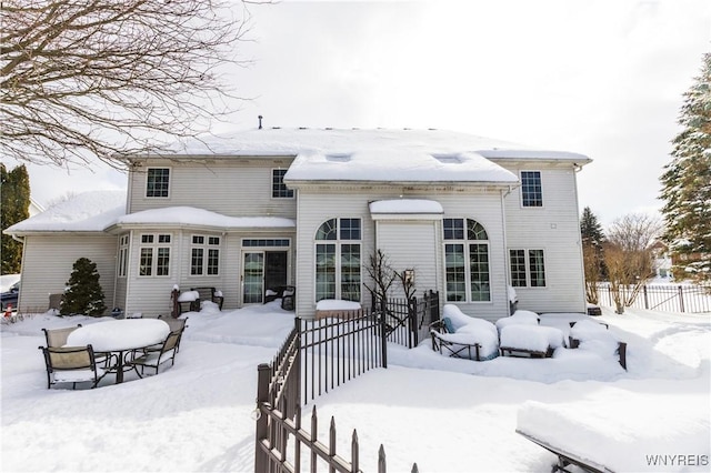 snow covered back of property with fence