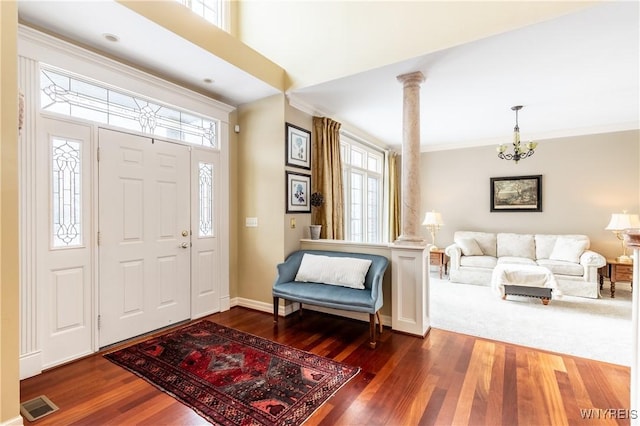 entryway featuring baseboards, visible vents, dark wood-style floors, crown molding, and ornate columns