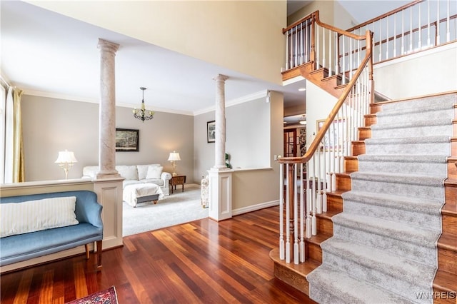 interior space featuring crown molding, decorative columns, baseboards, and wood finished floors