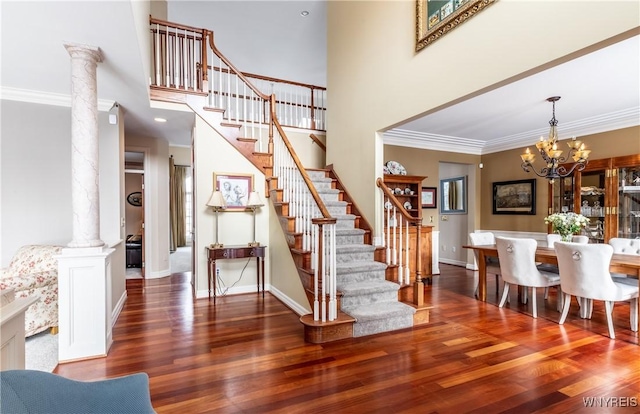 stairway with ornamental molding, ornate columns, and wood finished floors