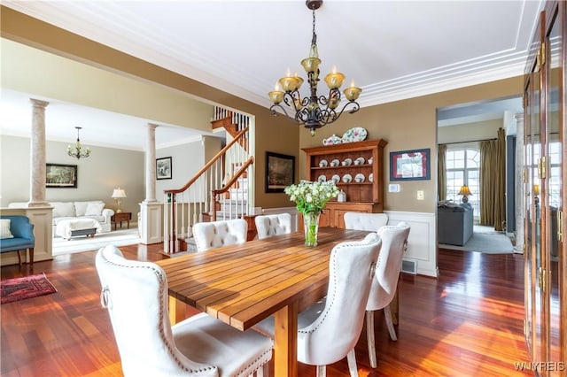 dining room with crown molding, dark wood-style floors, decorative columns, and an inviting chandelier