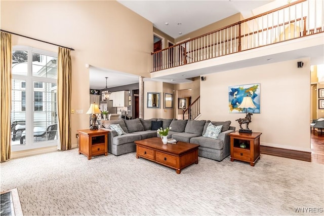 living area with a towering ceiling, stairway, carpet, and baseboards