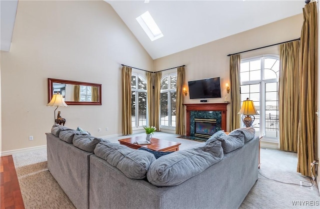 living area with high vaulted ceiling, a skylight, baseboards, and a premium fireplace