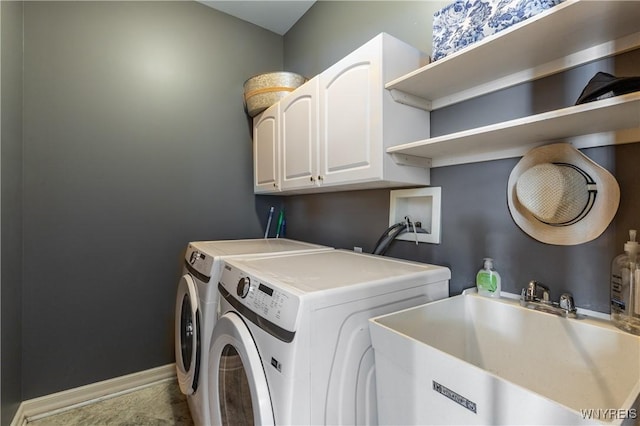 clothes washing area with cabinet space, baseboards, washer and clothes dryer, and a sink