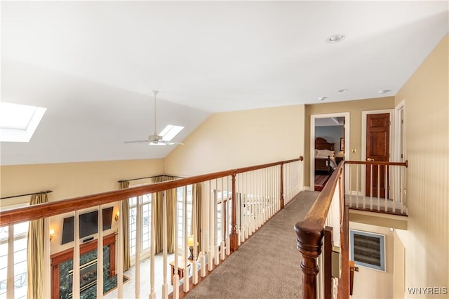 hallway with vaulted ceiling with skylight and carpet flooring