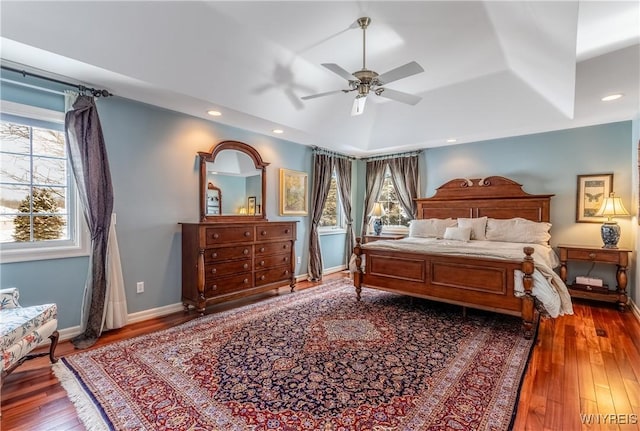 bedroom with a tray ceiling, baseboards, hardwood / wood-style floors, and recessed lighting