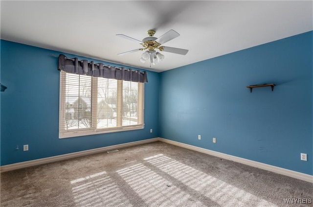 carpeted spare room featuring visible vents, baseboards, and a ceiling fan