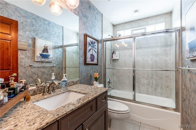 bathroom featuring toilet, vanity, bath / shower combo with glass door, and tile patterned floors