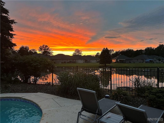 patio terrace at dusk with a fenced in pool and fence