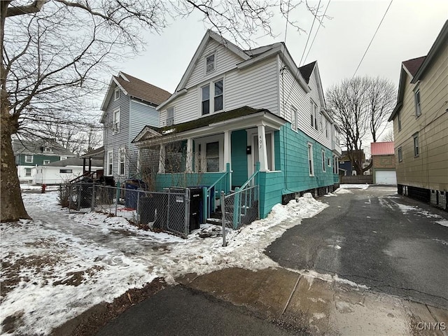 view of front facade featuring covered porch, an outbuilding, and fence