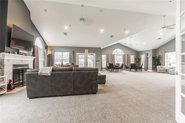 living area featuring carpet floors, french doors, a premium fireplace, ceiling fan, and high vaulted ceiling