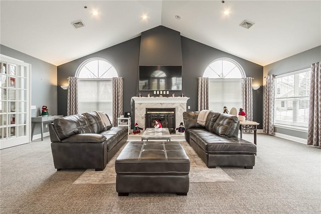 living area with a fireplace, visible vents, vaulted ceiling, and carpet flooring