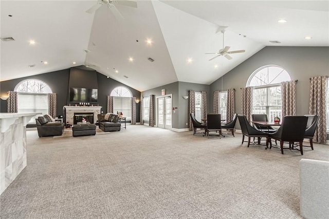 carpeted living area featuring high vaulted ceiling, visible vents, a fireplace, and ceiling fan