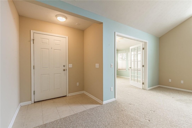 foyer with light carpet, baseboards, and light tile patterned floors