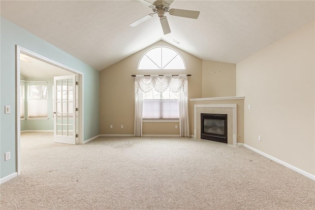 unfurnished living room featuring vaulted ceiling, carpet floors, a tile fireplace, and a wealth of natural light