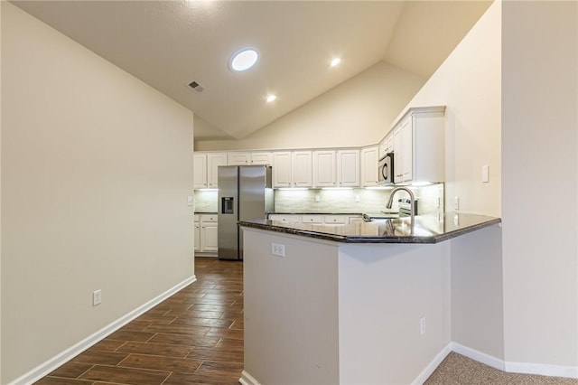 kitchen with visible vents, decorative backsplash, appliances with stainless steel finishes, a peninsula, and white cabinetry