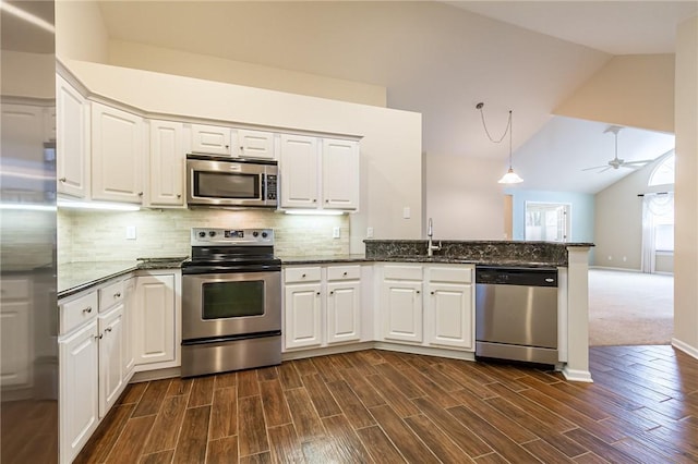 kitchen featuring a peninsula, a sink, white cabinets, vaulted ceiling, and appliances with stainless steel finishes