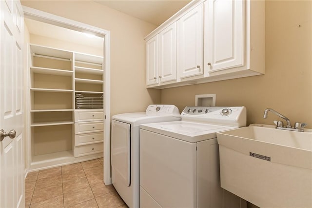 laundry area with light tile patterned floors, washer and clothes dryer, a sink, and cabinet space