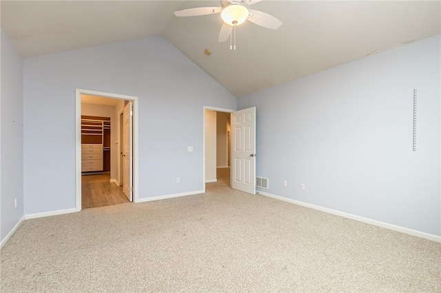 unfurnished bedroom featuring light colored carpet, visible vents, vaulted ceiling, ceiling fan, and baseboards